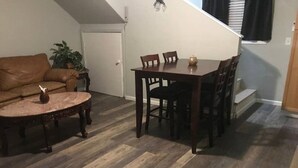 Ein Essbereich mit einem Holztisch und Stühlen, einer braunen Ledercouch und einem Blumentopf.