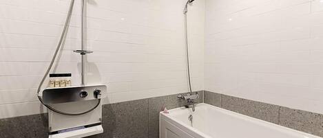 A bathroom with a bathtub, a shower, and a towel rack with a towel dispenser.