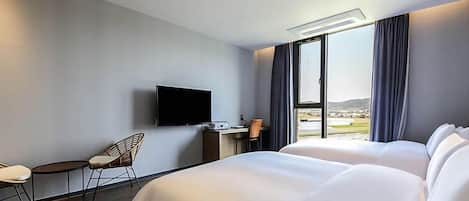 Habitación de hotel con cama, escritorio, silla, televisor y ventana con vistas.
