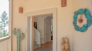 A covered porch with a wooden ceiling, a cactus decoration, a bear sculpture, and a turquoise wreath on the wall. - View of White Sands/Tularosa Basin, hot tub & a/c in the Village of Cloudcroft! (Cloudcroft)