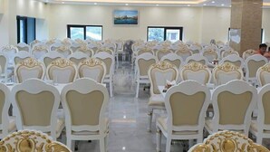 A banquet hall with rows of ornate chairs and tables, recessed ceiling lighting, and large windows. - Phoenix Hotel 2 (Sam Son)