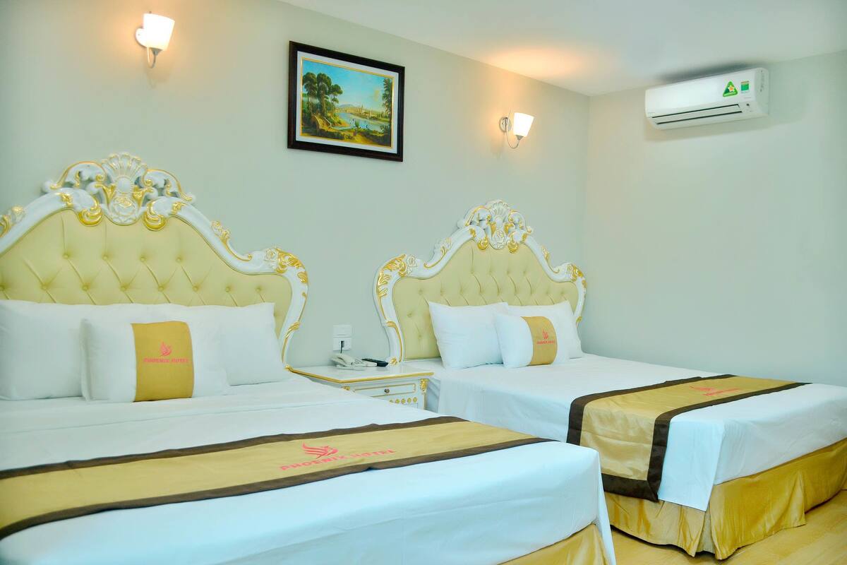 Une chambre d’hôtel avec deux lits, chacun doté d’une tête de lit et d’un pied de lit, une table de chevet avec une lampe et un appareil de climatisation fixé au mur.