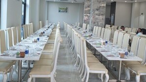 A conference room with long tables, white chairs, and a marble column. - Phoenix Hotel 2 (Sam Son)