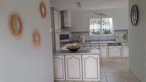 Een keuken met witte kasten, een fornuis en een raam met uitzicht op groen.
