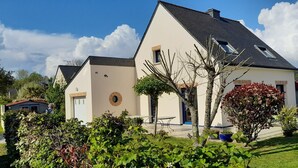 Een modern huis met twee verdiepingen, een schuin dak, een rond raam en een kleine aaneengebouwen garage.