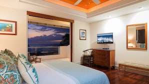 Une chambre avec un grand lit, un bureau, une télévision et une vue sur l’océan.