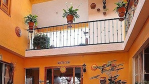 A reception area with a balcony, potted plants, and leather furniture. - Hotel Camelinas Área Blanca (Patzcuaro)
