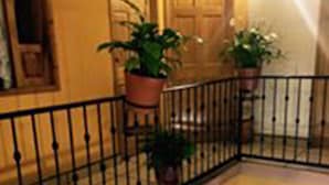 A multi-level interior with a black metal railing, wooden doors, and potted plants. - Hotel Camelinas Área Blanca (Patzcuaro)