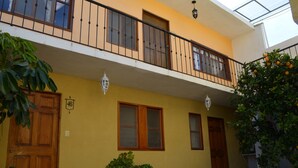 A yellow building with a balcony, wooden doors, and potted plants. - Hotel Camelinas Área Blanca (Patzcuaro)
