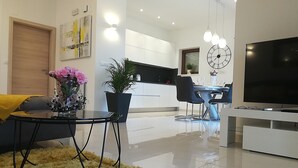 Un salon moderne comprenant un canapé, une table basse, un téléviseur et un coin repas avec des chaises et une table.
