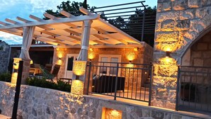 Un bâtiment en pierre doté d’une pergola et d’un espace extérieur aménagé pour s’asseoir.