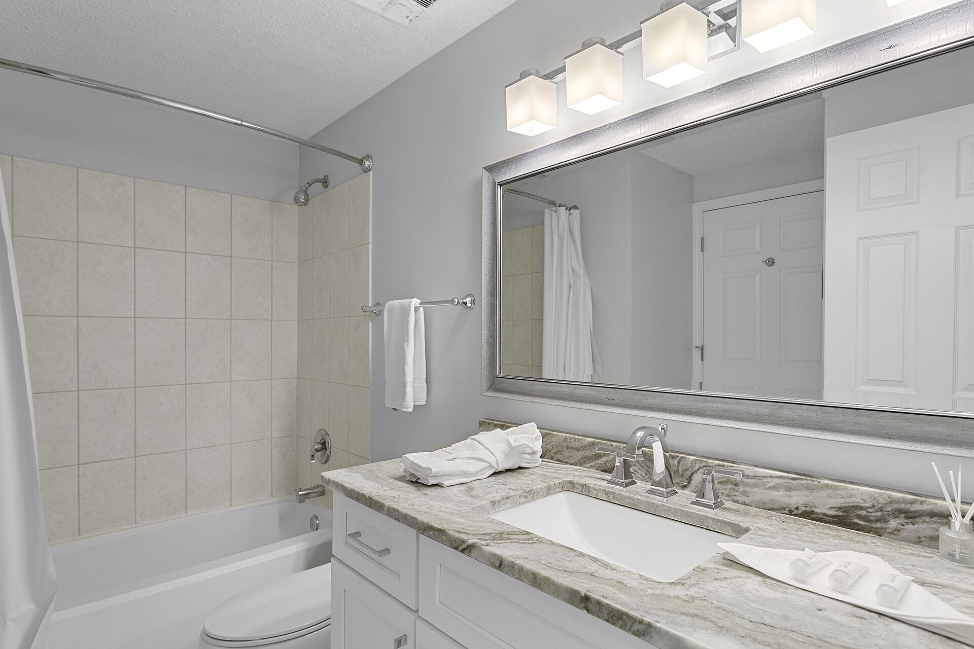 Un baño moderno con bañera, lavabo con espejo y perchero para toallas.