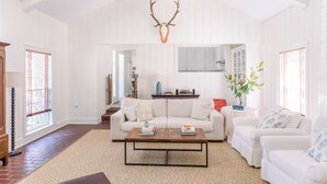 A spacious living room with a high ceiling, white walls, a large sofa, a coffee table, and a mounted deer skull. - Large family home - walking distance to campus and square! (Oxford)