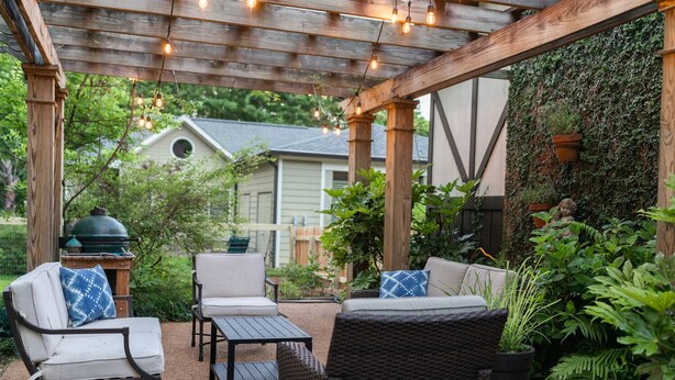 An outdoor patio with wooden furniture, string lights, and a green wall with plants. - Large family home - walking distance to campus and square! (Oxford)