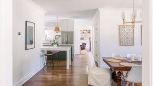 A modern kitchen with a central island, white cabinetry, and a hanging pendant light. - Large family home - walking distance to campus and square! (Oxford)