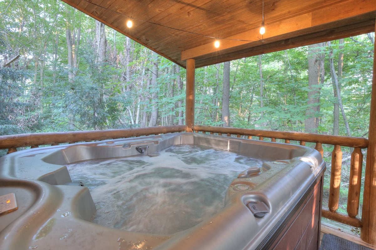 Un jacuzzi en una terraza de madera con vistas al bosque.