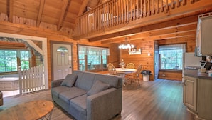 Interior acogedor de una cabaña con comedor de madera, un sofá y una cocina con mostrador de madera.