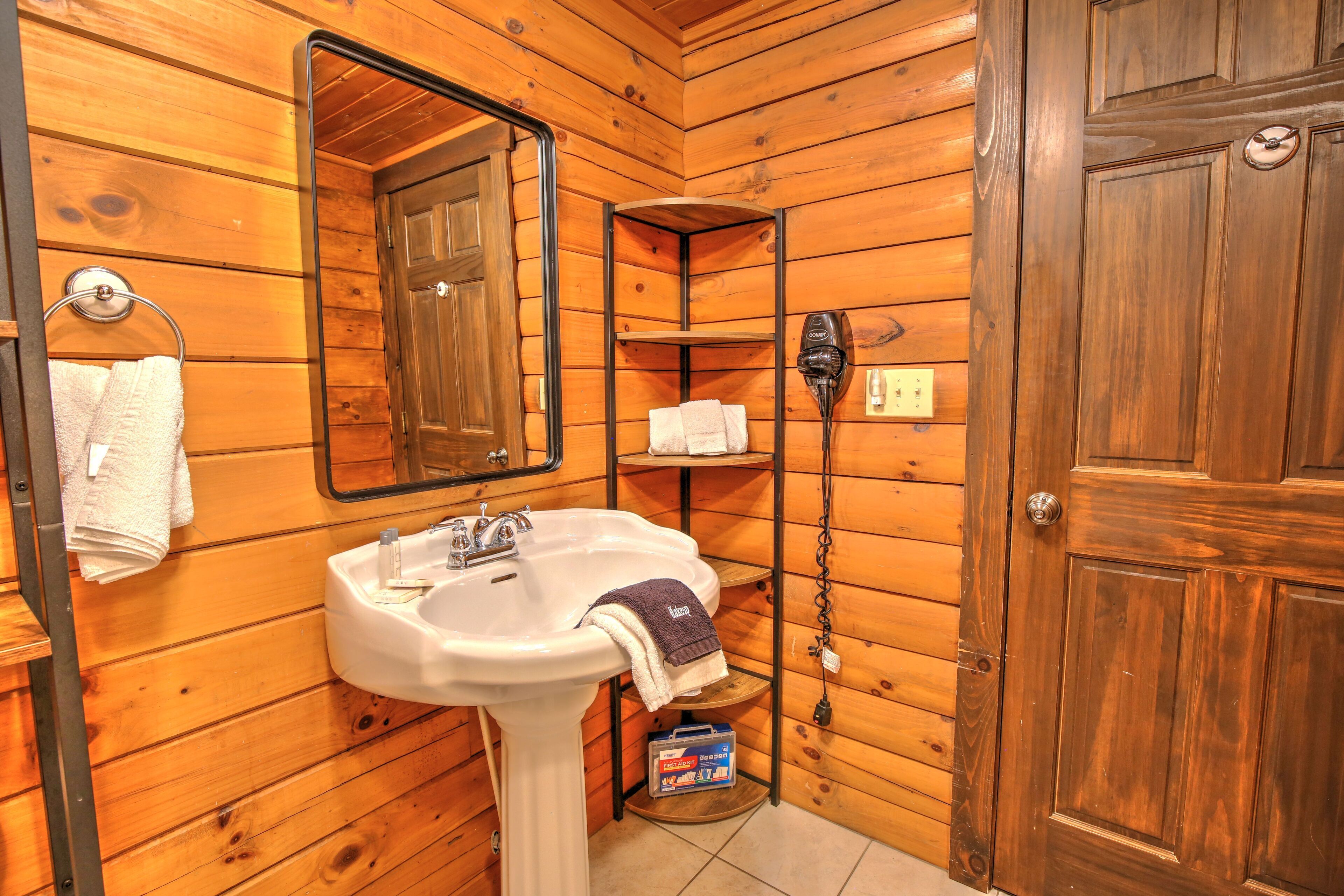 A wooden-paneled bathroom with a white sink, a mirror, and a towel rack.