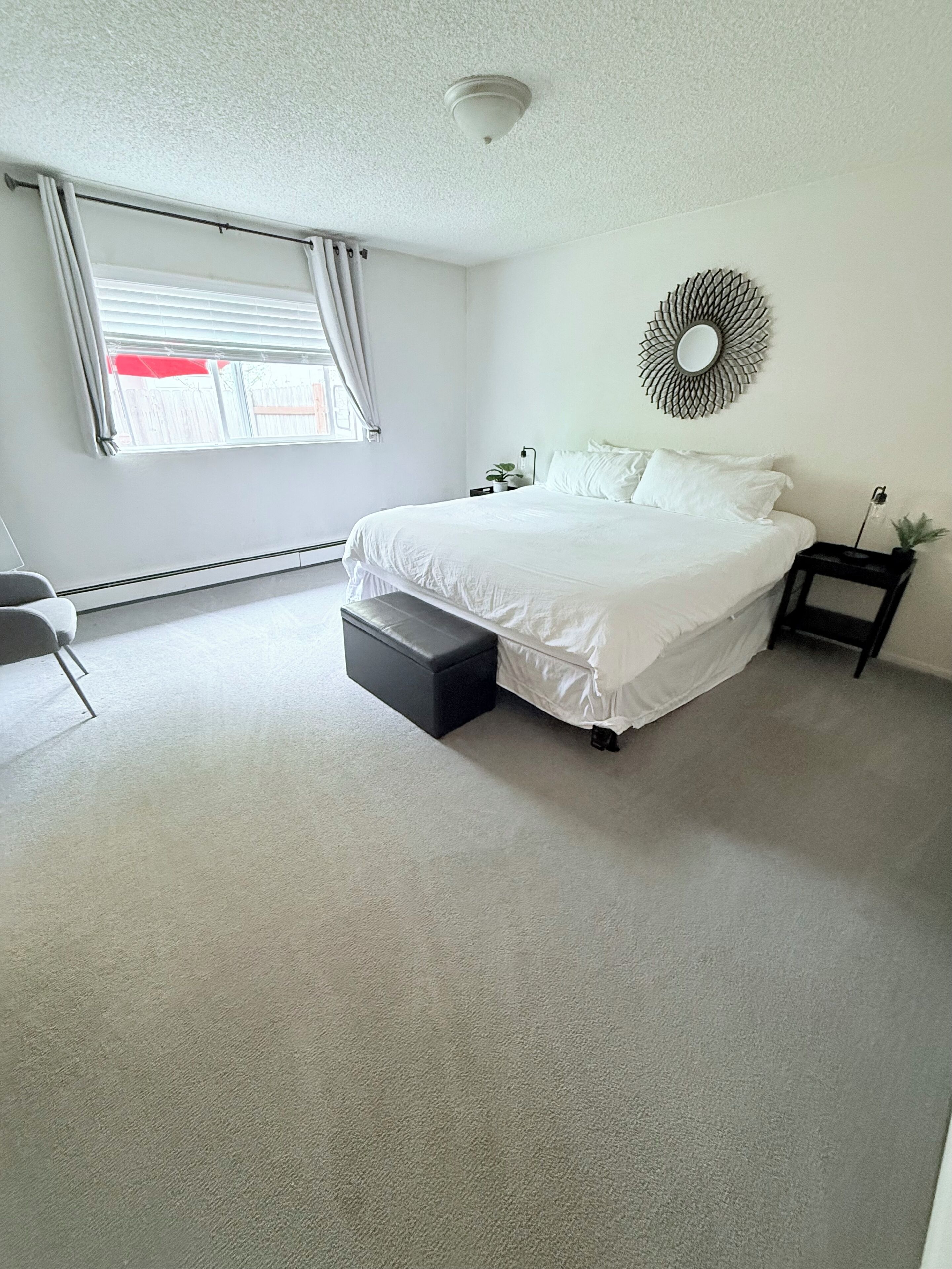Une chambre à coucher avec un grand lit, une table de chevet, une chaise et un élément décoratif mural.