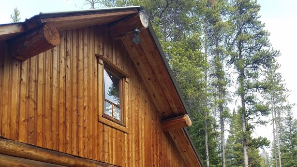 A log cabin with a deck, large sliding glass doors, and a small window.