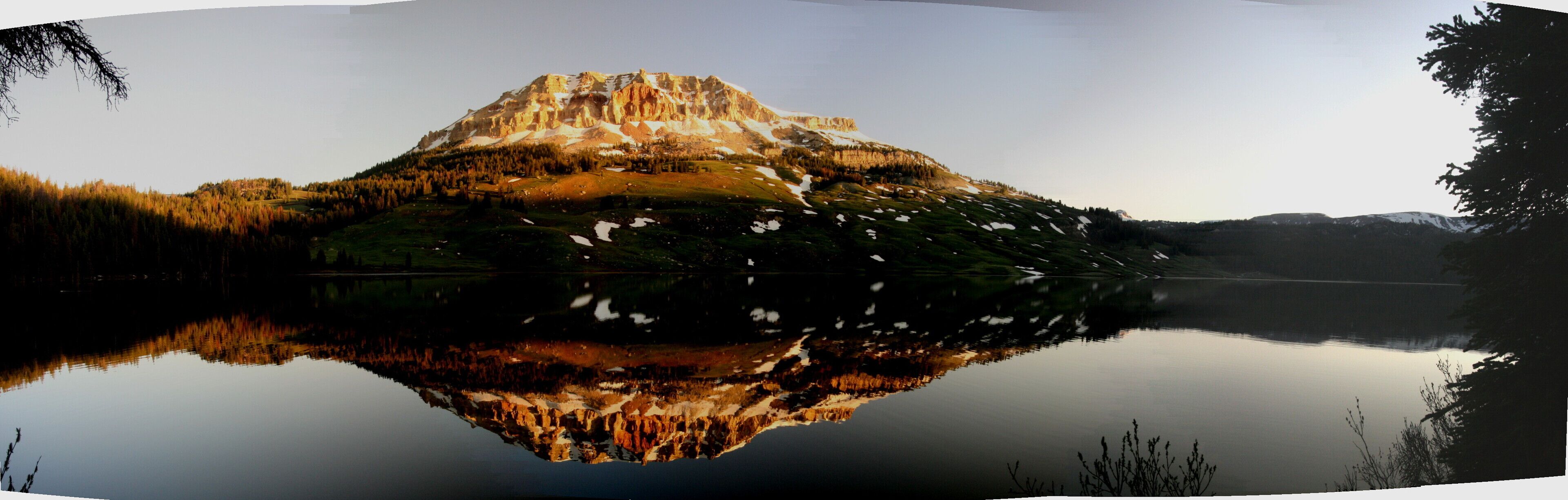 Ein Berg spiegelt sich in einem ruhigen See unter blauem Himmel.