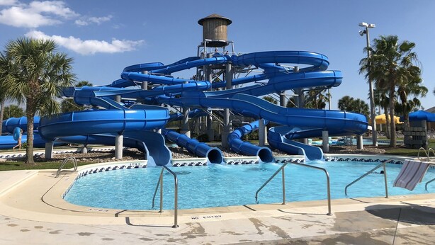 Ein Wasserpark mit mehreren blauen Rutschen und einem Pool.