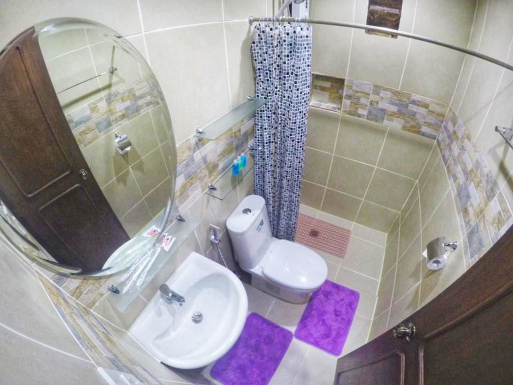 A bathroom with a glass-enclosed shower, a toilet, and a sink.