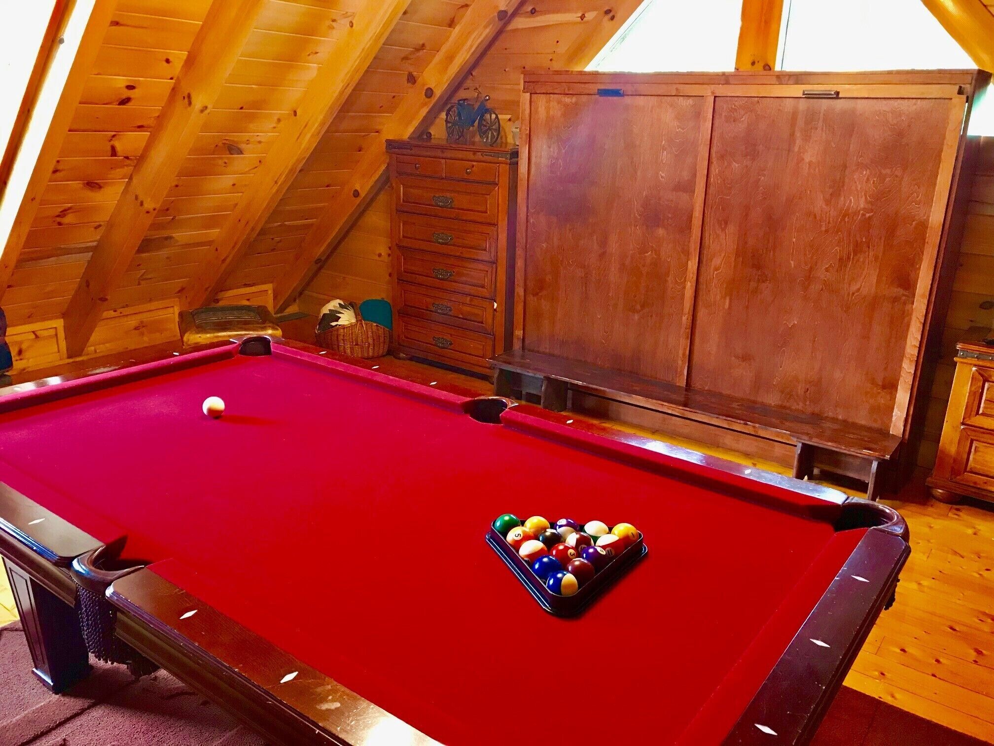 A pool table in a room with wooden walls and a sloped ceiling.
