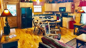 A cozy cabin interior with a wooden dining area, kitchen, and living space.