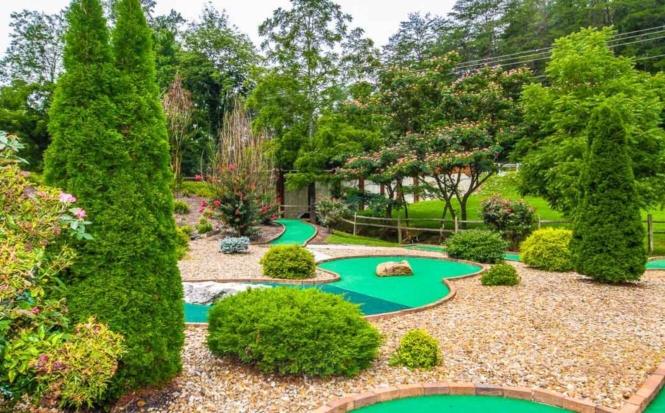 A landscaped garden with a winding path, neatly trimmed bushes, and a variety of trees.