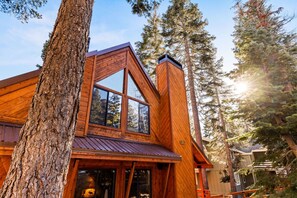 Een houten chalet met grote ramen, een schuin dak en een schoorsteen.