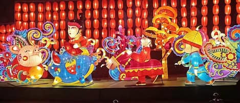 Un escenario iluminado con faroles chinos tradicionales y figuras coloridas e iluminadas.