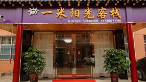 A hotel entrance with a red carpet, glass doors, and two potted plants. - One Meter Sunshine Xi'an Xianyang International Airport Hotel (Xianyang)