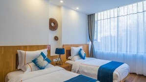 A hotel room with two beds, a wooden headboard, a wall-mounted lamp, and a window with curtains. - One Meter Sunshine Xi'an Xianyang International Airport Hotel (Xianyang)