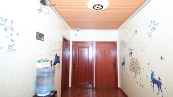 A hallway with wooden flooring, two wooden doors, and a water dispenser on the left.