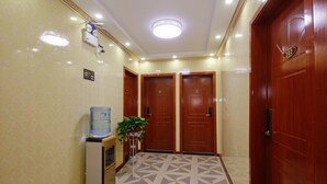 A hotel lobby with a water dispenser, a plant, and two wooden doors. - One Meter Sunshine Xi'an Xianyang International Airport Hotel (Xianyang)