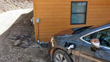 A car parked next to a wooden building with a window and electrical outlets.