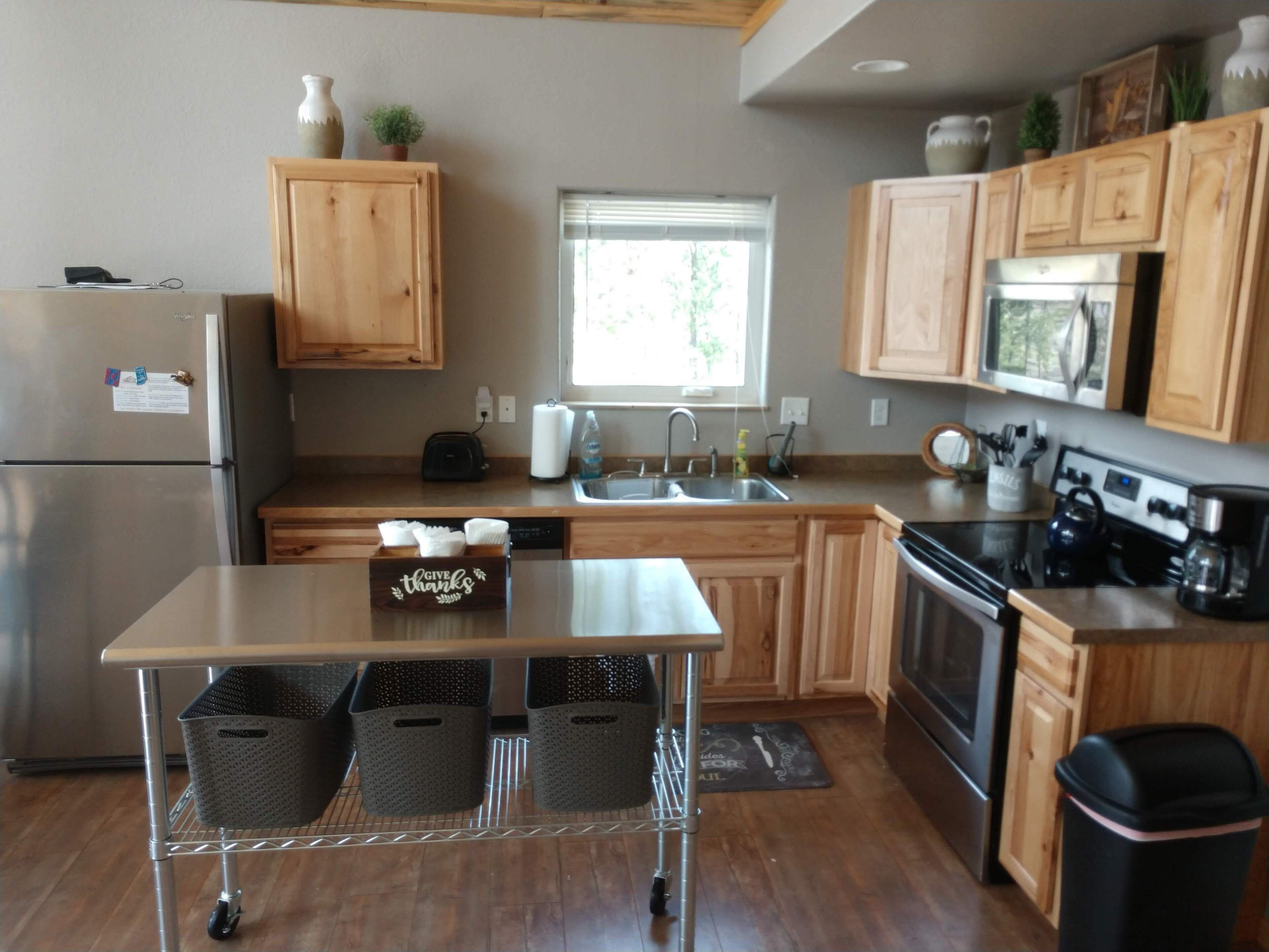 A modern kitchen with wooden cabinets, stainless steel appliances, and a central island with baskets.