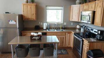 A modern kitchen with wooden cabinets, stainless steel appliances, and a central island with baskets.