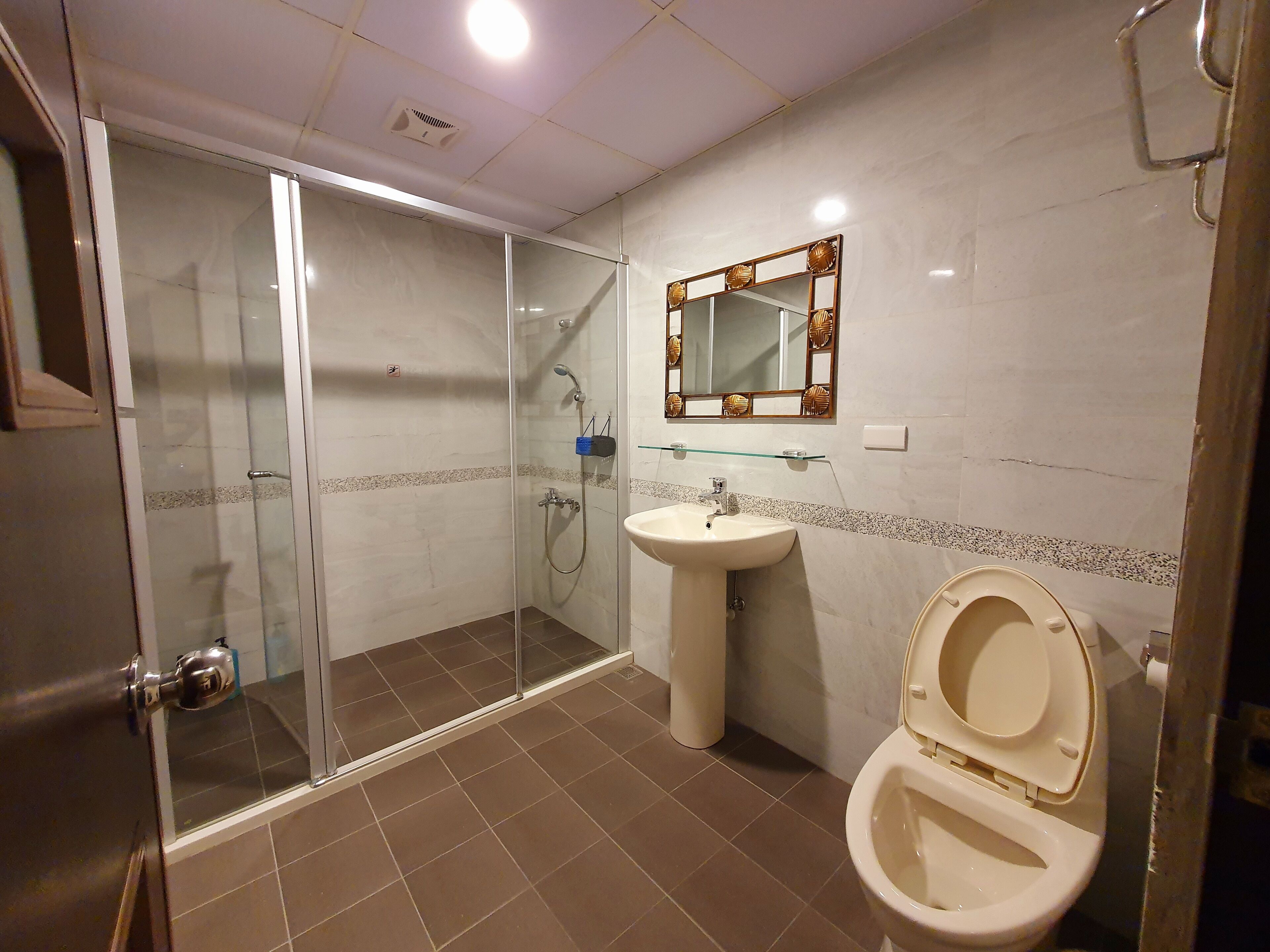 Un baño con ducha acristalada, lavabo e inodoro.