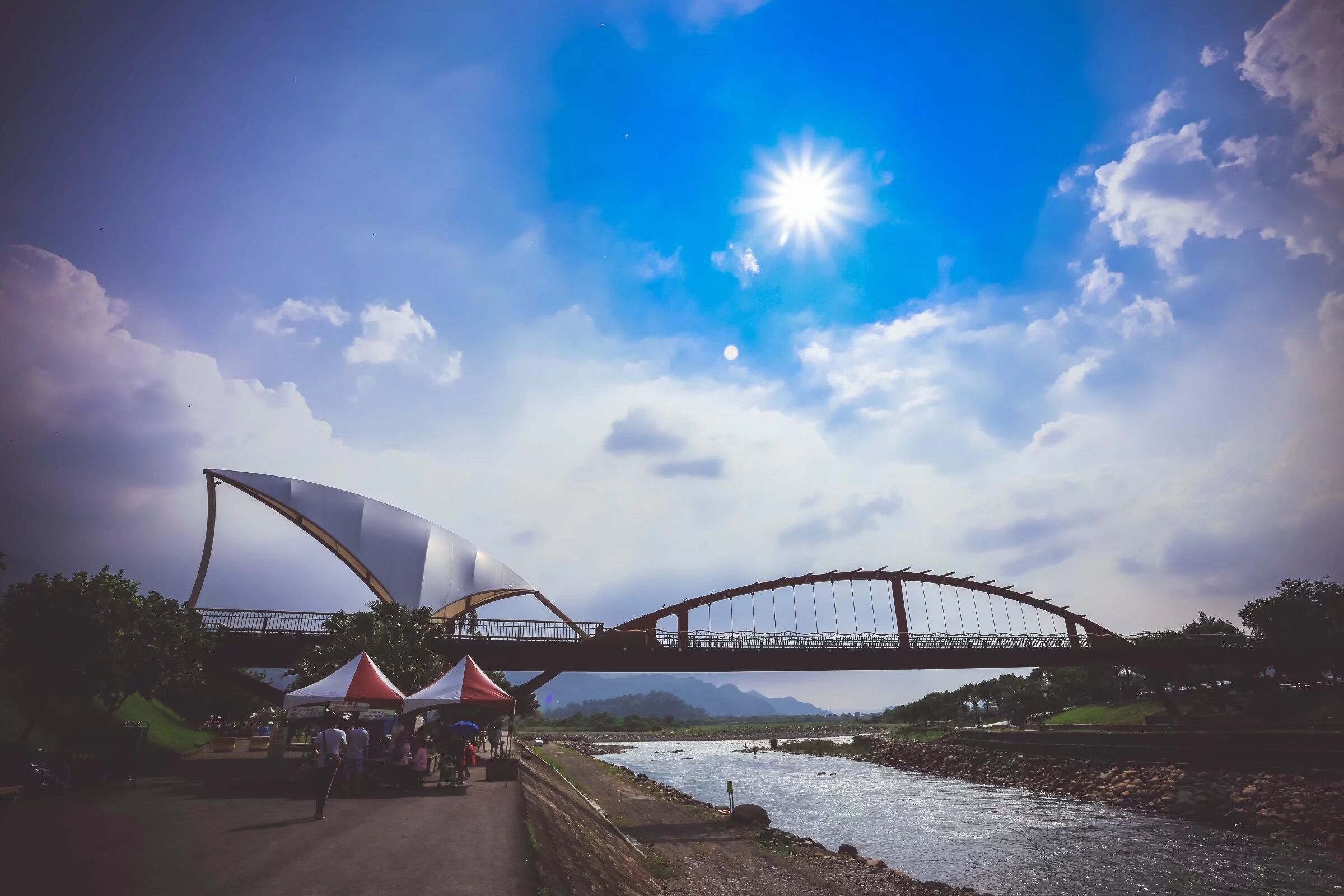 A bridge over a river with tents on the side.