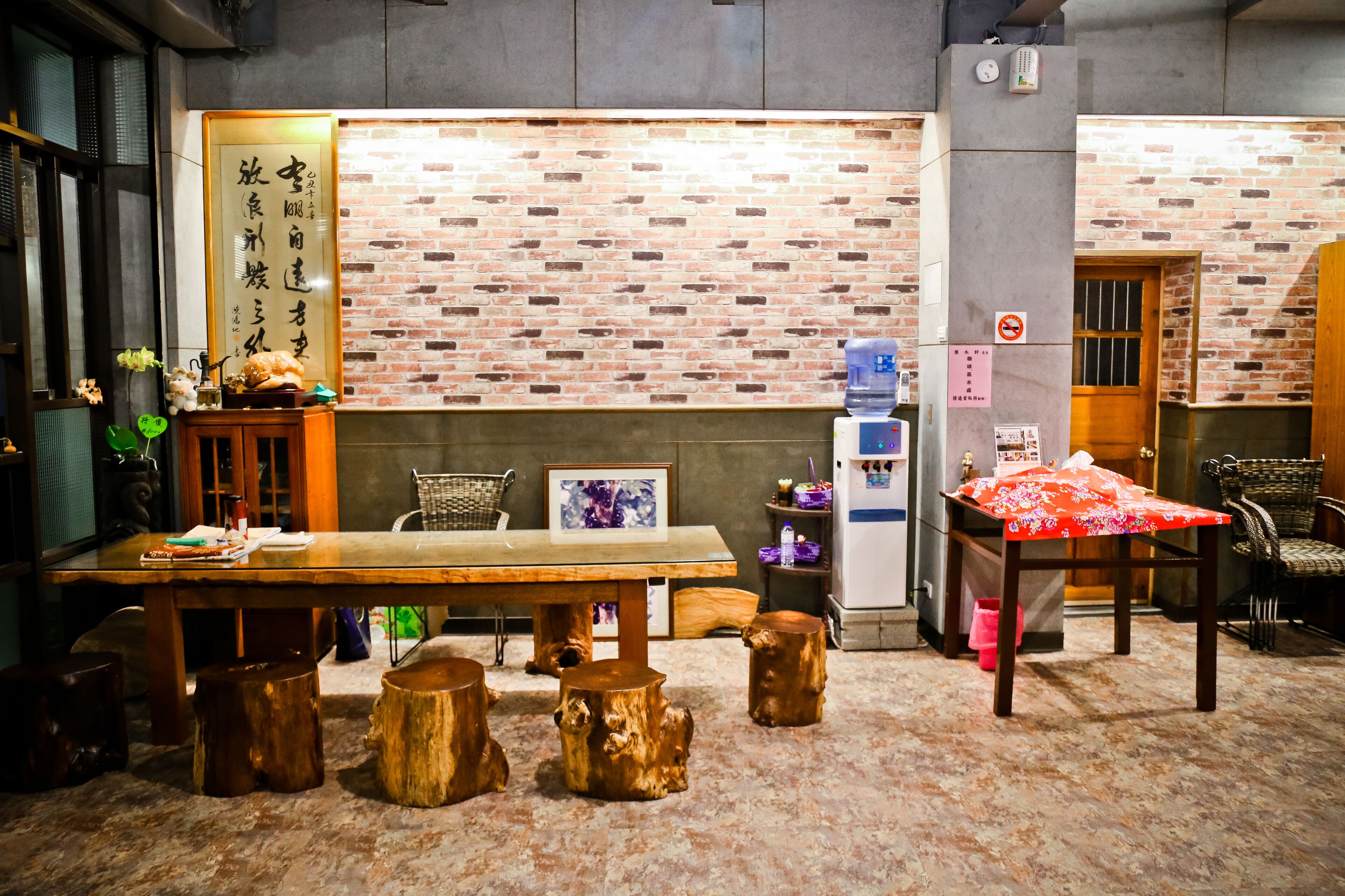 A traditional Japanese-style room with a wooden table, stools, and a brick wall.
