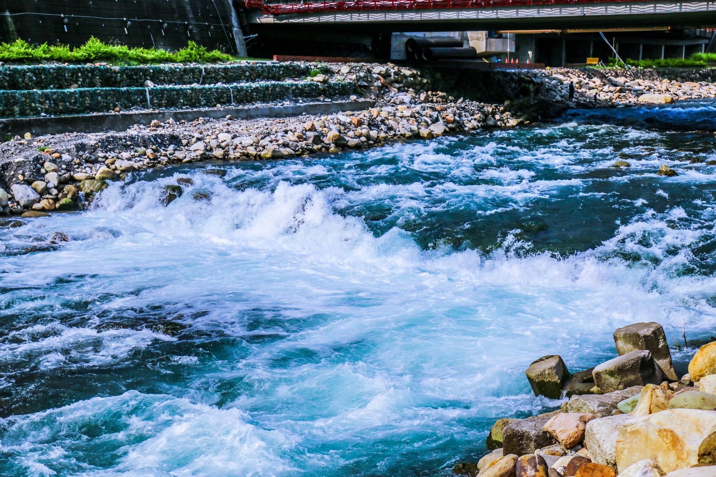 A river with rocks and a bridge in the background.
