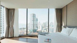 A hotel room with a large bed, a view of a cityscape, and curtains on the windows. - Em Oi Boutique Hotel (Nha Trang)