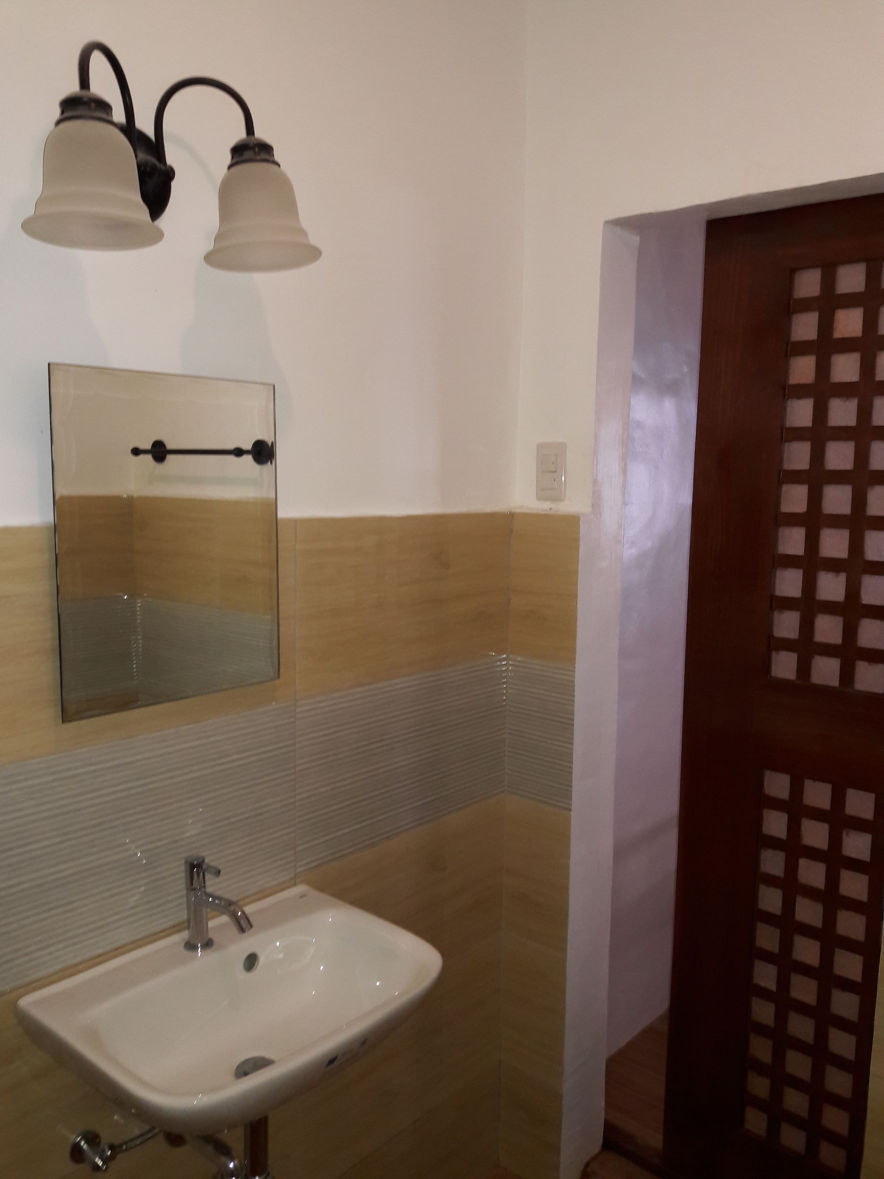 A bathroom with a white sink, a mirror, and two wall-mounted lights.