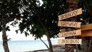 A wooden signpost with directions to Boracay, Key West, Lanikai, and Bon Bon. - Carolina del Mar (Samboan)
