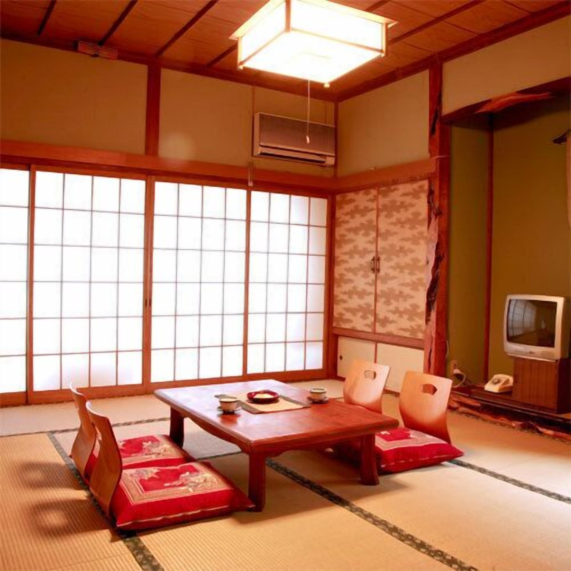 A traditional Japanese room with tatami flooring, a low wooden table, and a television.