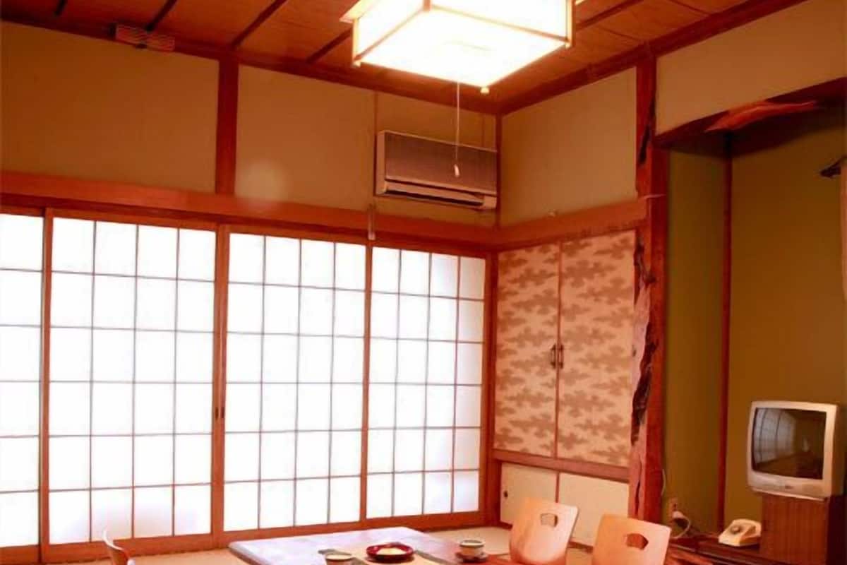 A traditional Japanese room with tatami flooring, a low wooden table, and a television.
