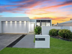 A modern house with a garage, a driveway, and a mailbox with the number 73.