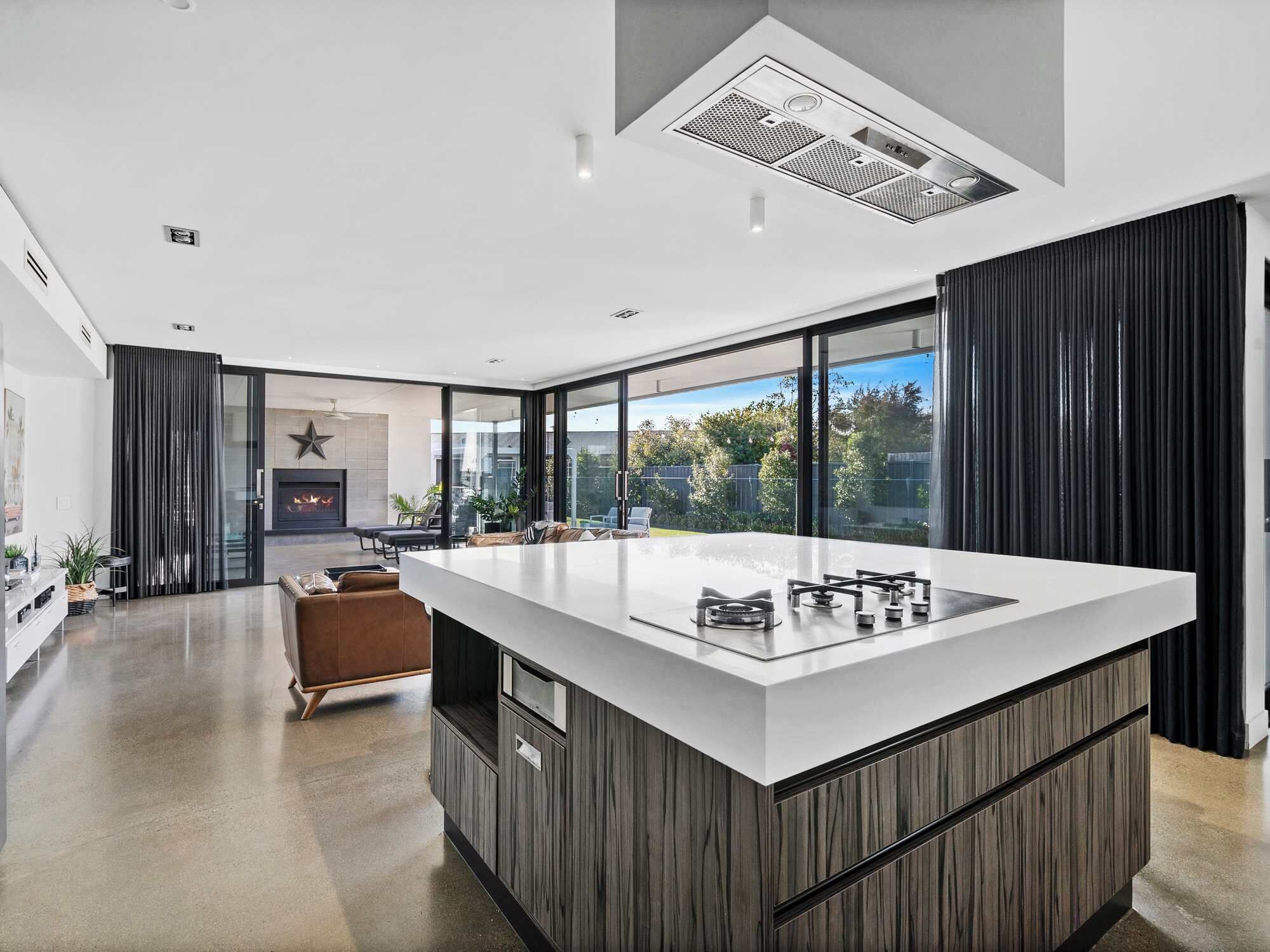 A modern kitchen with a large island, a fireplace, and a view of the outdoors.